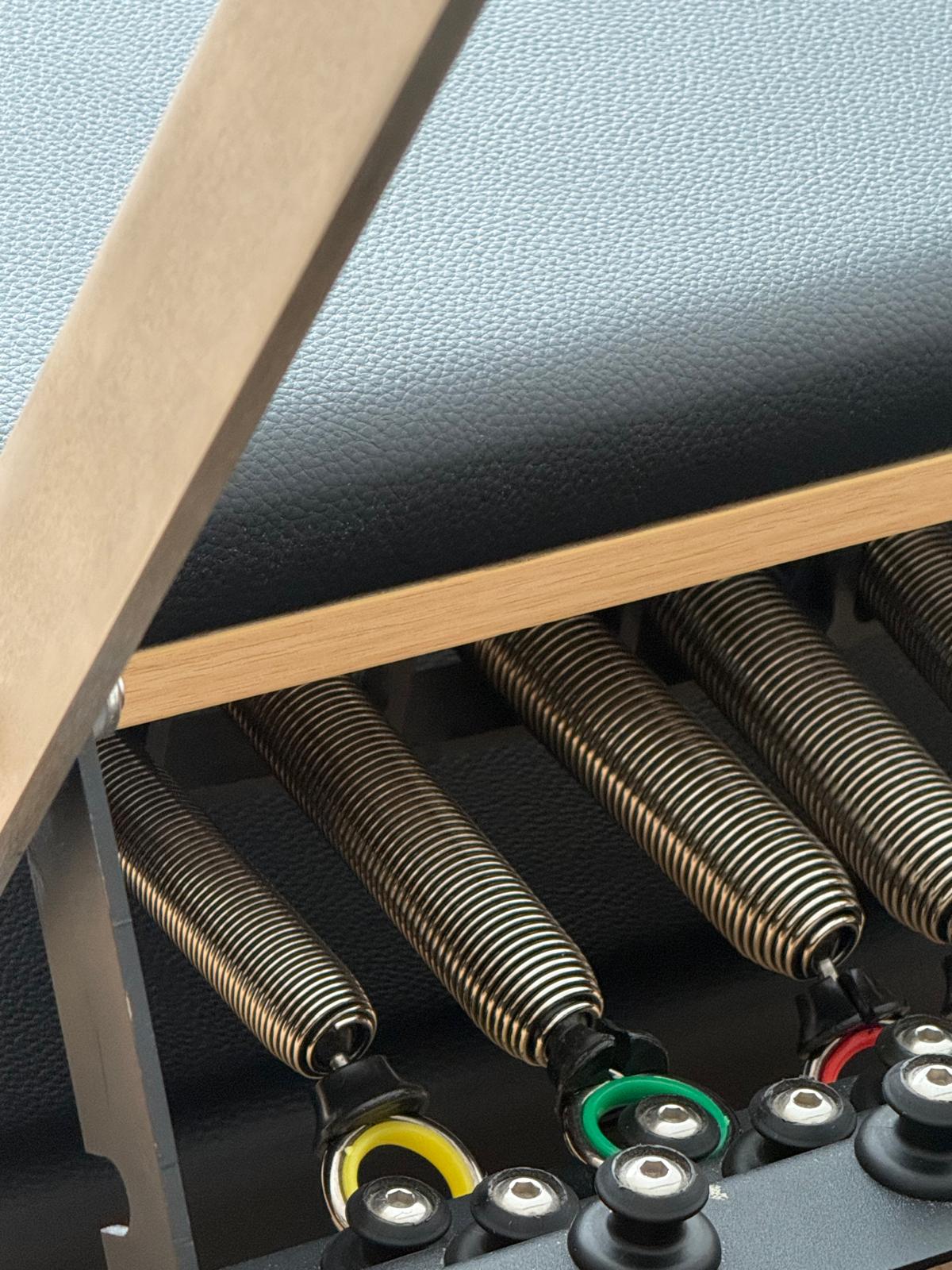 Detalle de muelles y estructura de un reformer de Pilates.